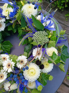 Nahaufnahme des Blumenkranzes mit Gerbera-Blumen und blauen Elementen
